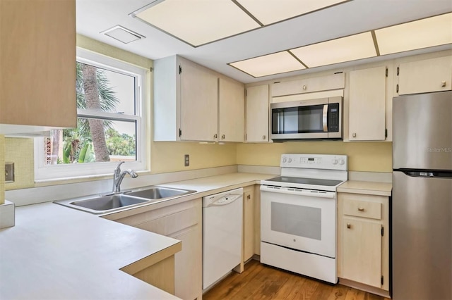 kitchen with hardwood / wood-style flooring, stainless steel appliances, cream cabinetry, and sink