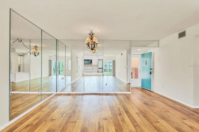 spare room featuring light hardwood / wood-style floors and a notable chandelier