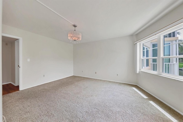 unfurnished room with carpet flooring, a notable chandelier, and a wealth of natural light