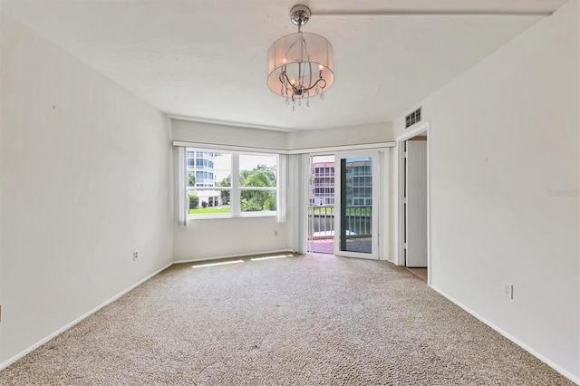 carpeted empty room featuring a chandelier