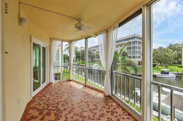 unfurnished sunroom with a water view, ceiling fan, and a healthy amount of sunlight