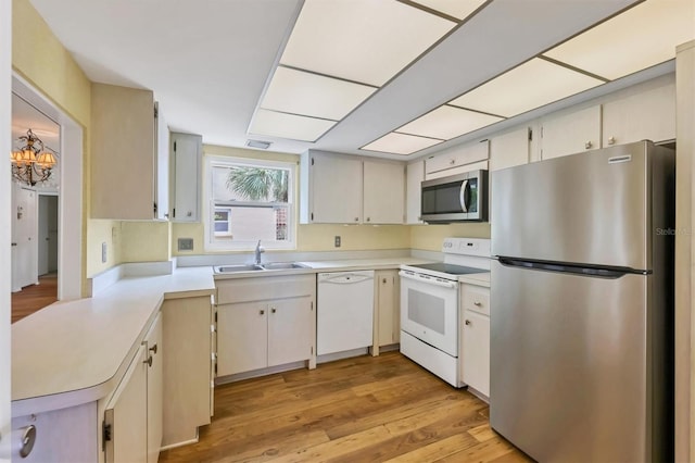1300 N Portofino Dr Unit 208, Sarasota, FL 34242 - kitchen featuring stainless steel appliances, light countertops, light wood-type flooring, and a peninsula