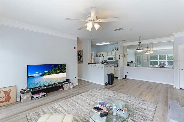 living room with ceiling fan, ornamental molding, and light wood-type flooring