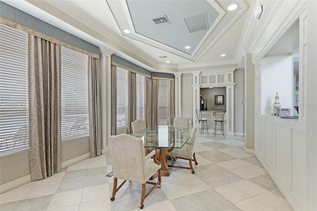 tiled dining area featuring decorative columns, crown molding, and a tray ceiling