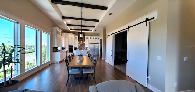 dining room featuring dark wood-type flooring, beam ceiling, and a barn door