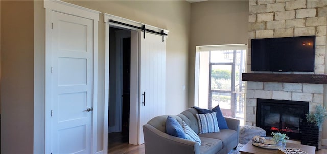 living room featuring a barn door, hardwood / wood-style floors, and a fireplace