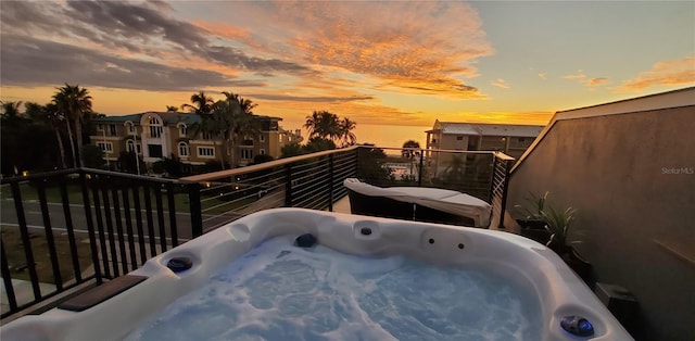 patio terrace at dusk with a balcony and a hot tub