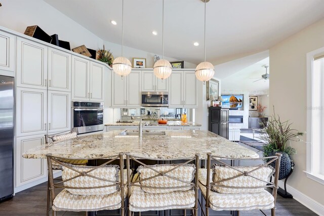 kitchen with decorative light fixtures, sink, a breakfast bar area, stainless steel appliances, and a center island with sink