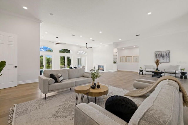 living room featuring light hardwood / wood-style floors, ceiling fan, and ornamental molding