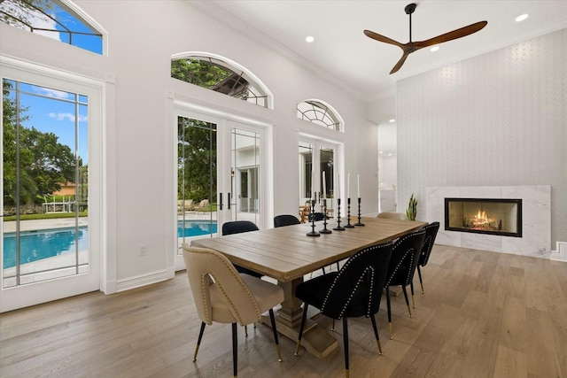 dining room featuring ceiling fan, french doors, crown molding, light hardwood / wood-style floors, and a fireplace