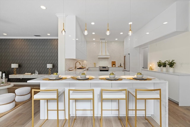 kitchen featuring white cabinetry, pendant lighting, and custom range hood