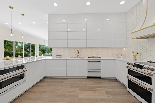 kitchen with stainless steel oven, custom range hood, pendant lighting, range, and white cabinetry