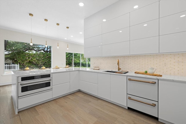 kitchen featuring white cabinets, oven, sink, decorative backsplash, and decorative light fixtures