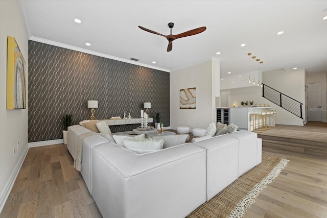 living room with ceiling fan, light hardwood / wood-style floors, crown molding, and beverage cooler