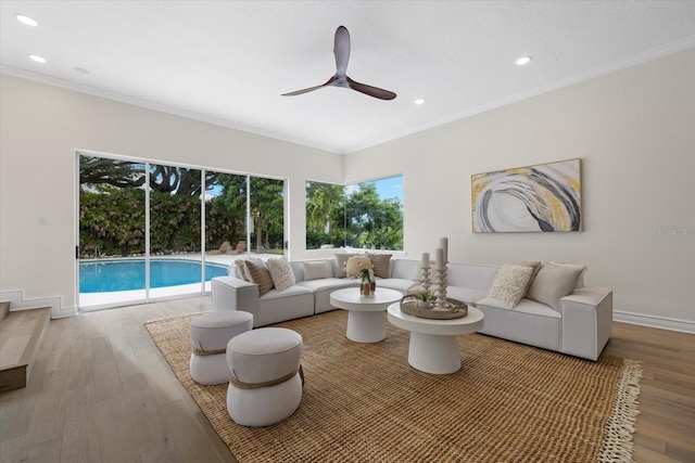 living room featuring hardwood / wood-style flooring, ceiling fan, and crown molding