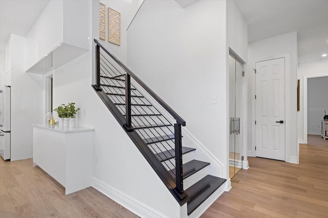 staircase with a towering ceiling and wood-type flooring