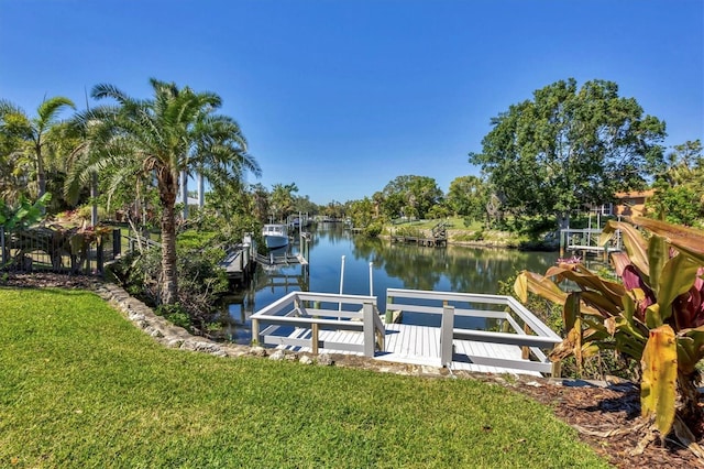 view of dock featuring boat lift, a water view, and a lawn