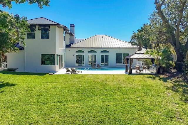 rear view of property featuring a gazebo, a yard, a patio area, and an outdoor pool