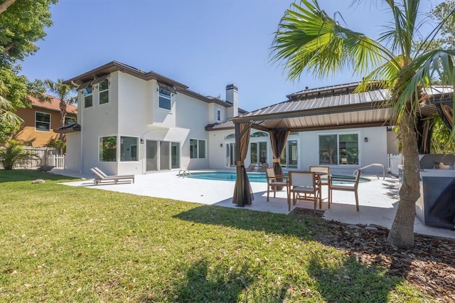 rear view of property featuring a patio area, a yard, and fence