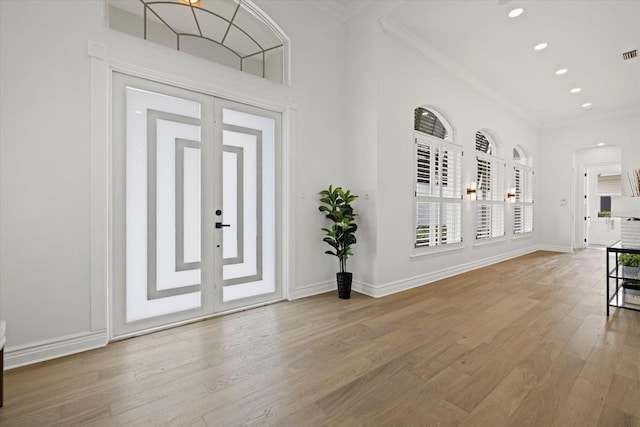 entrance foyer featuring ornamental molding, wood finished floors, arched walkways, and baseboards