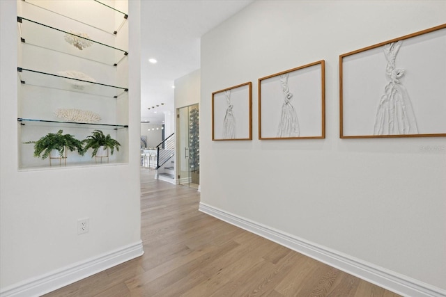 hall featuring baseboards, wood finished floors, and stairs