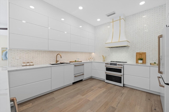 kitchen with white appliances, custom exhaust hood, a sink, white cabinetry, and modern cabinets