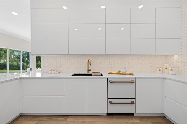 kitchen with a sink, light wood-style flooring, modern cabinets, and white cabinets