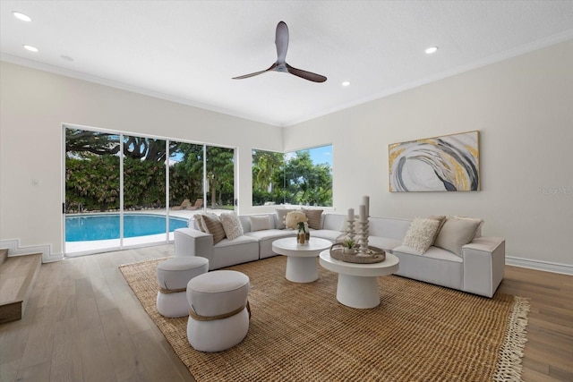 living area featuring ornamental molding, ceiling fan, baseboards, and wood finished floors