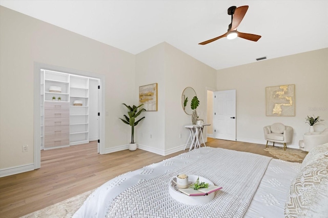 bedroom featuring a ceiling fan, baseboards, visible vents, light wood-style flooring, and a spacious closet