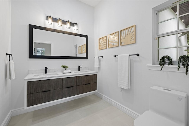 bathroom with a sink, baseboards, toilet, and double vanity