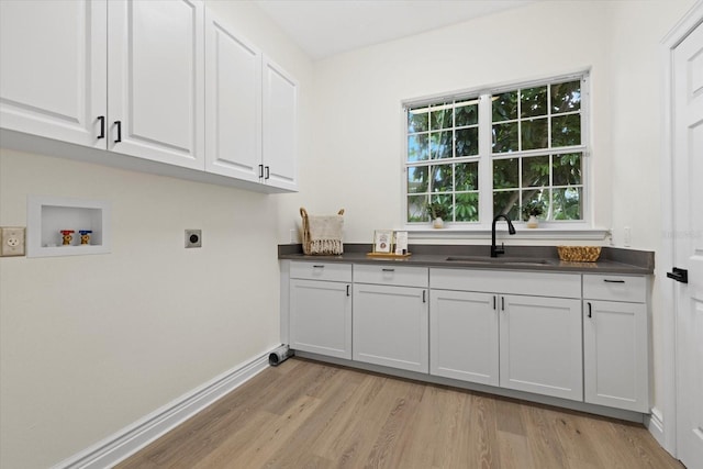 washroom with hookup for a washing machine, cabinet space, electric dryer hookup, a sink, and light wood-type flooring