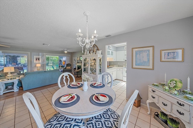 tiled dining area featuring ceiling fan with notable chandelier and a textured ceiling