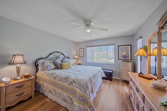 bedroom featuring ceiling fan, light hardwood / wood-style flooring, and a textured ceiling