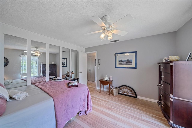 bedroom featuring ceiling fan, a textured ceiling, and light wood-type flooring