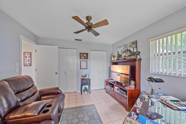 tiled living room featuring ceiling fan and a textured ceiling