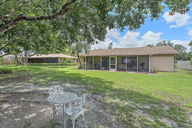 back of property with a lawn and a sunroom