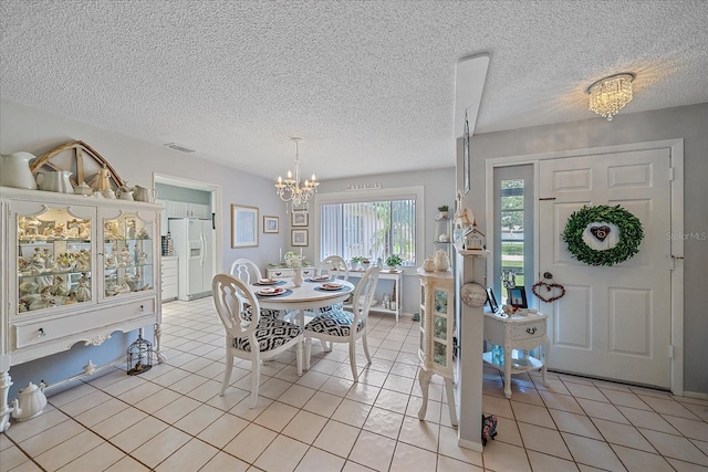 tiled dining area with a chandelier and a textured ceiling