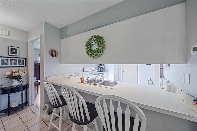 kitchen featuring sink, white electric range, a textured ceiling, and light tile patterned floors