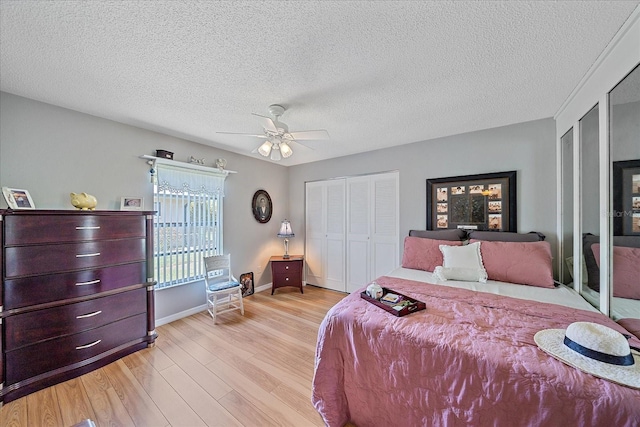 bedroom featuring multiple closets, ceiling fan, a textured ceiling, and light wood-type flooring