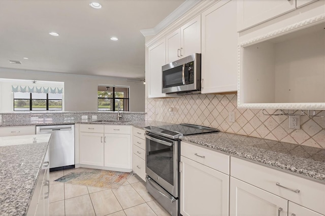 kitchen with light stone countertops, sink, light tile patterned floors, white cabinets, and appliances with stainless steel finishes