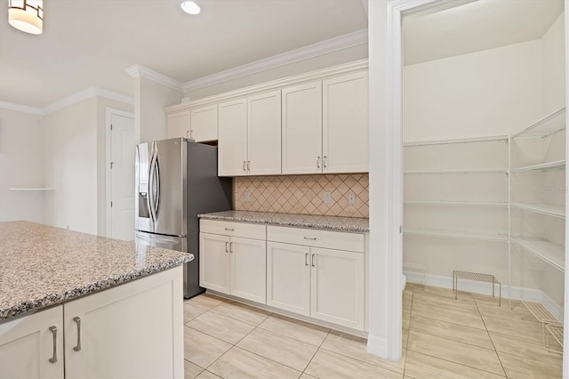 kitchen with light stone countertops, stainless steel fridge, tasteful backsplash, light tile patterned floors, and white cabinets