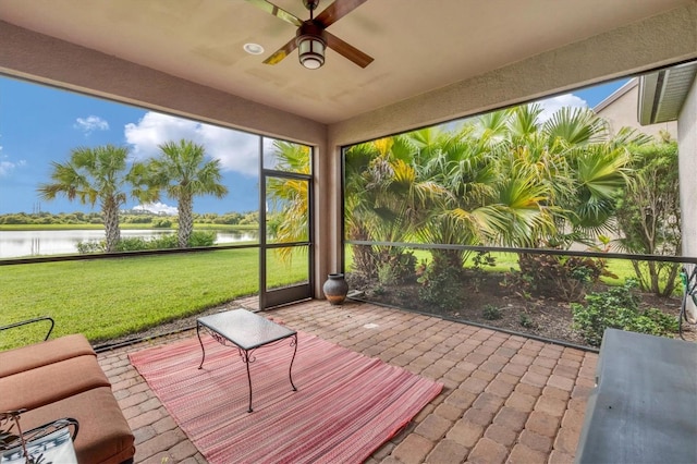 unfurnished sunroom featuring ceiling fan and a water view