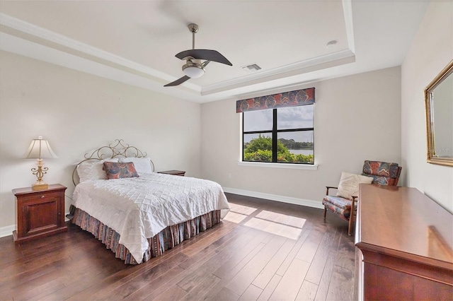 bedroom featuring ceiling fan, dark hardwood / wood-style floors, and a raised ceiling