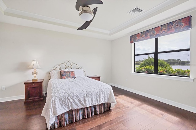 bedroom featuring ceiling fan, dark hardwood / wood-style flooring, a raised ceiling, and crown molding