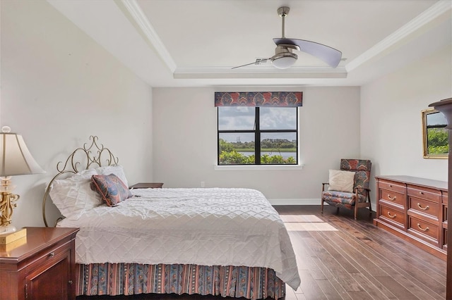 bedroom with dark hardwood / wood-style flooring, a raised ceiling, ceiling fan, and crown molding