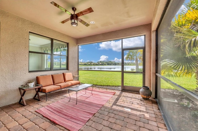 sunroom featuring ceiling fan and a water view