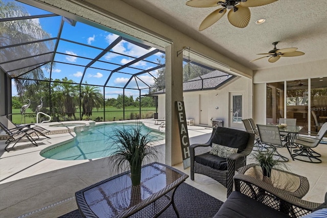 view of swimming pool with an in ground hot tub, a patio, glass enclosure, outdoor lounge area, and ceiling fan