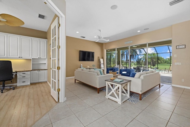 tiled living room with ceiling fan and built in desk