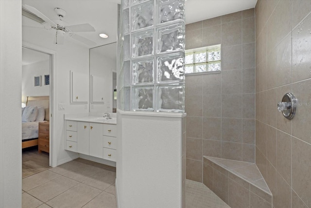 bathroom with ceiling fan, vanity, a tile shower, and tile patterned flooring