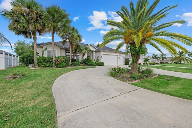 single story home with a garage, stucco siding, a front lawn, and curved driveway